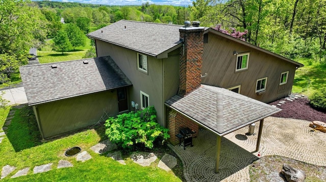 11675 New Biddinger Rd, Harrison Twp, OH 45030 - back of property featuring a view of trees, a chimney, a shingled roof, a patio, and a yard