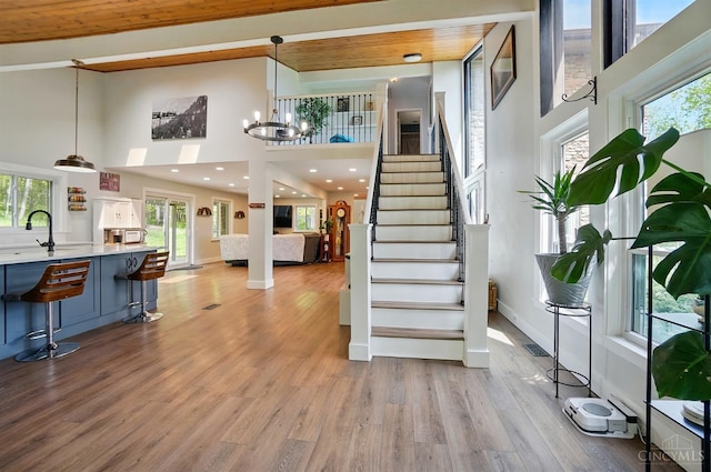 11675 New Biddinger Rd, Harrison Twp, OH 45030 - stairway with a high ceiling, healthy amount of natural light, a chandelier, wood finished floors, and baseboards