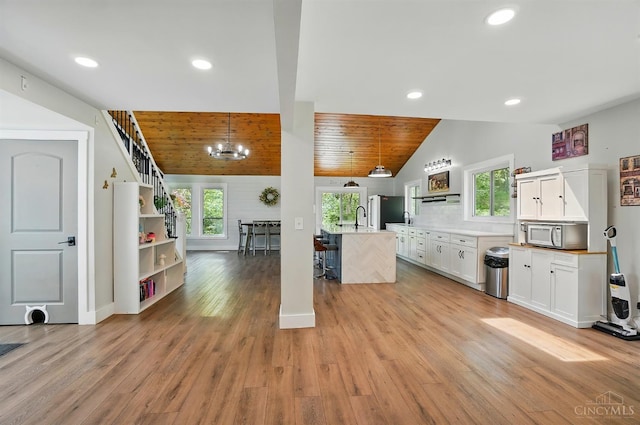 11675 New Biddinger Rd, Harrison Twp, OH 45030 - kitchen with vaulted ceiling, plenty of natural light, white cabinetry, light wood-style flooring, and a chandelier