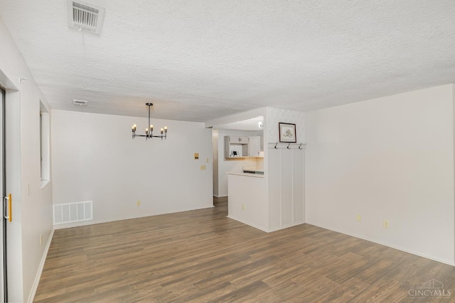 spare room with a chandelier, wood finished floors, a textured ceiling, and baseboards