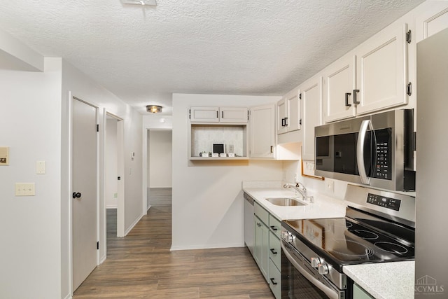 kitchen featuring appliances with stainless steel finishes, a sink, dark wood-type flooring, baseboards, and light countertops