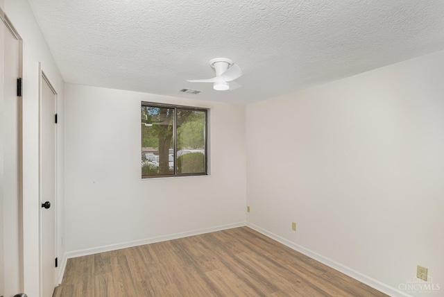 empty room with wood finished floors, baseboards, a textured ceiling, and ceiling fan