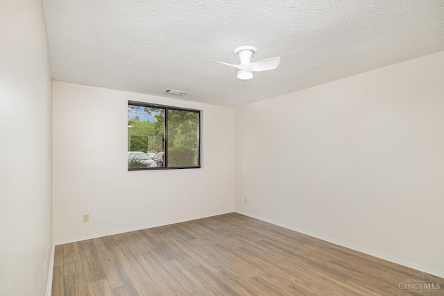 spare room featuring wood finished floors, a textured ceiling, and baseboards