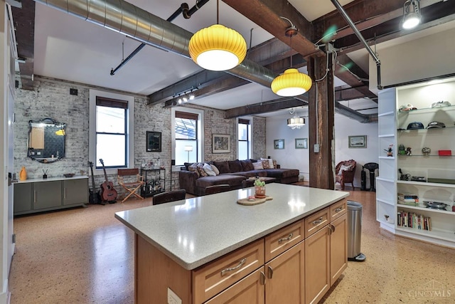 kitchen featuring open floor plan, dark aggregate flooring, decorative light fixtures, light countertops, and a kitchen island