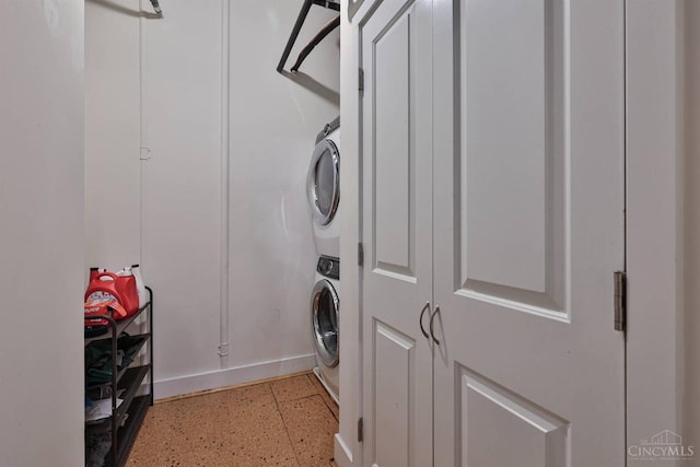 laundry area with stacked washer / dryer and baseboards