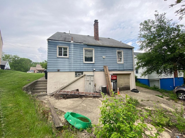 3518 Fyffe Ave, Cincinnati, OH 45211 - back of property with a chimney, an attached garage, driveway, and a lawn