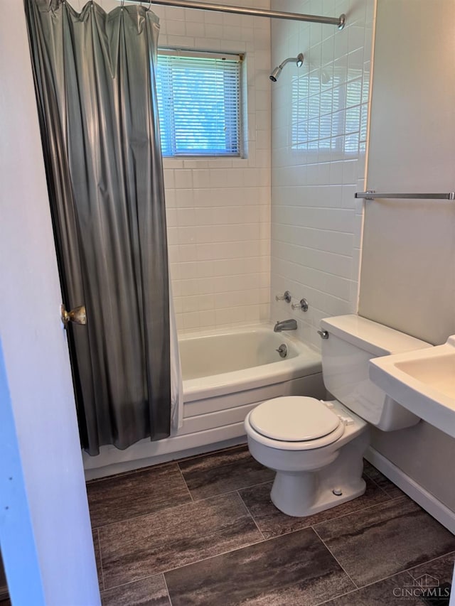 bathroom featuring shower / bath combo, toilet, and baseboards