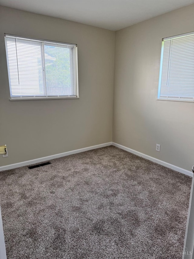 carpeted empty room featuring baseboards