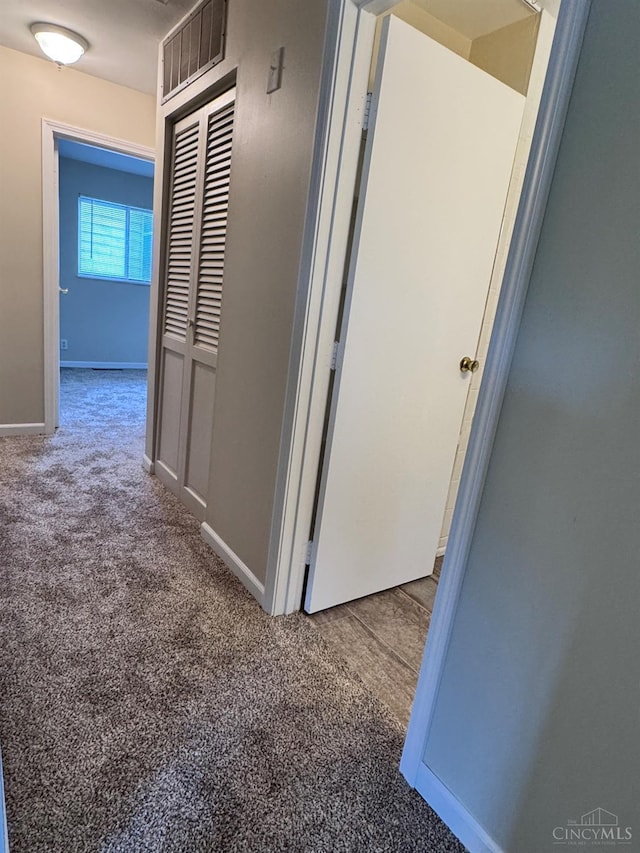 hallway featuring carpet flooring and baseboards