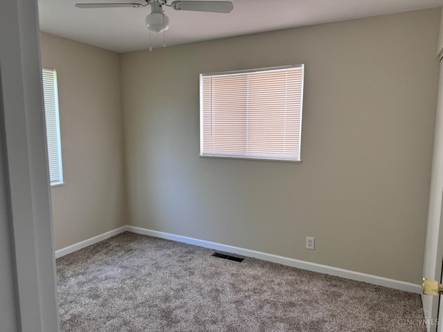 carpeted spare room with a ceiling fan and baseboards