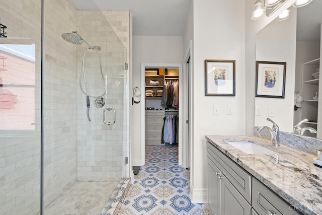 full bath with a shower stall, vanity, and a walk in closet