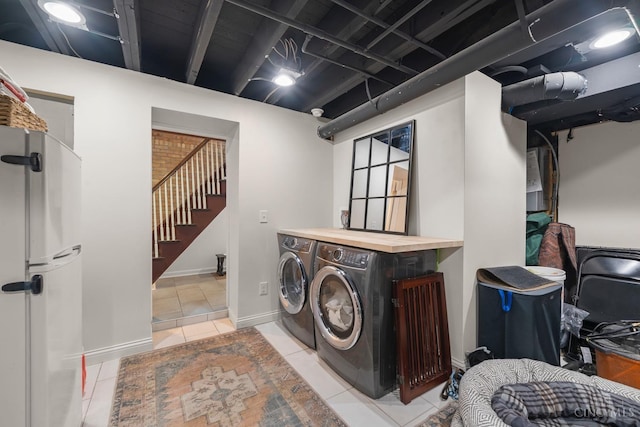 laundry room featuring washing machine and dryer, light tile patterned floors, and baseboards
