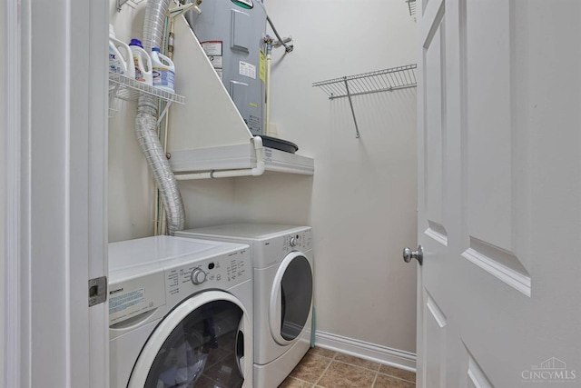 washroom featuring baseboards, washer and clothes dryer, and electric water heater