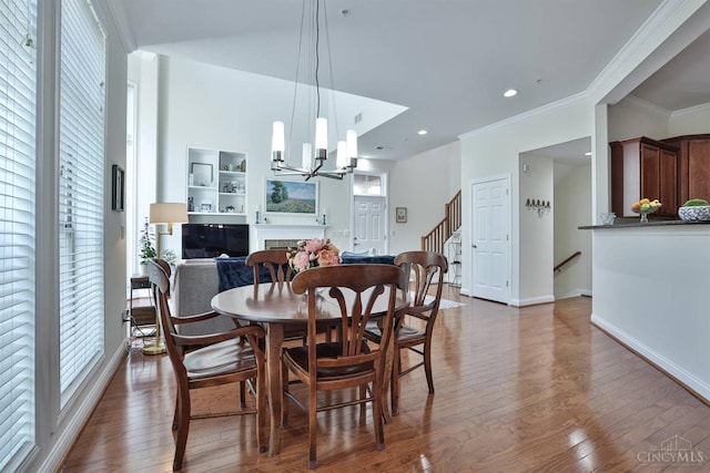 dining space featuring ornamental molding, hardwood / wood-style floors, baseboards, stairs, and a chandelier