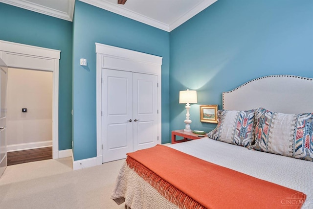 carpeted bedroom with ornamental molding, a closet, and baseboards