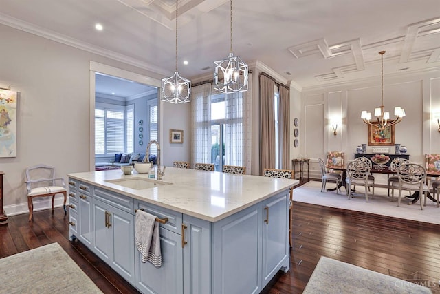 kitchen with a chandelier, a sink, dark wood-type flooring, crown molding, and a center island with sink
