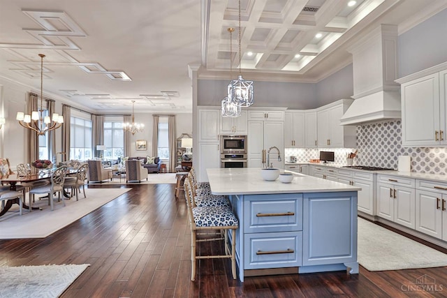 kitchen featuring a chandelier, appliances with stainless steel finishes, white cabinetry, light countertops, and an island with sink