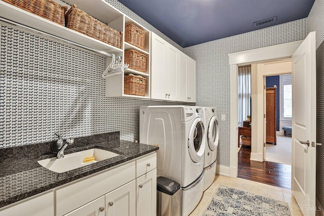 laundry room with washing machine and clothes dryer, light tile patterned floors, and cabinet space