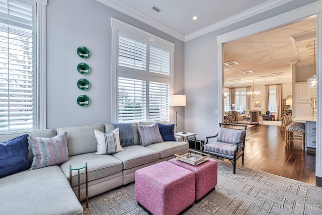 living room with healthy amount of natural light, a chandelier, hardwood / wood-style flooring, crown molding, and recessed lighting