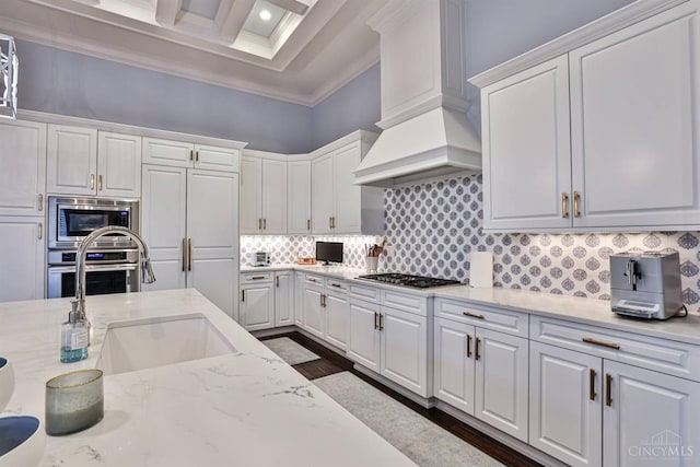 kitchen with stainless steel appliances, coffered ceiling, white cabinetry, ornamental molding, and backsplash