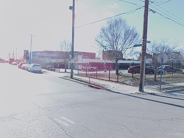 view of asphalt street featuring sidewalks, curbs, and traffic signs