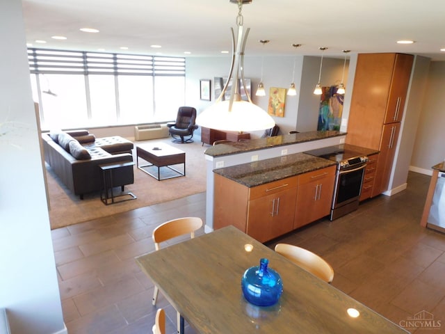 kitchen featuring stainless steel range with electric cooktop, brown cabinets, a peninsula, recessed lighting, and dark stone counters
