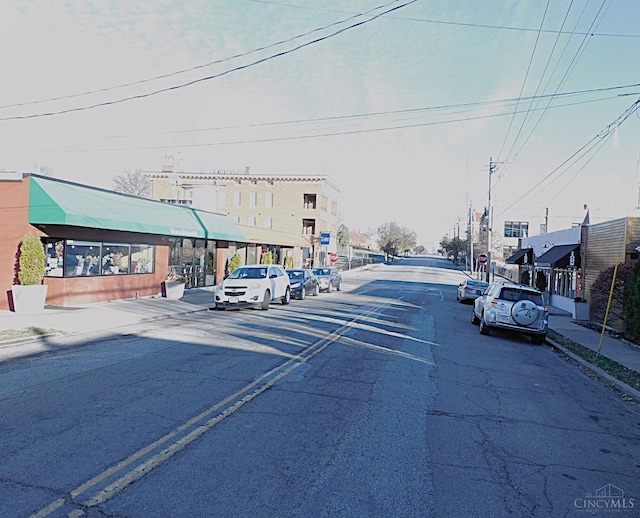view of asphalt road featuring sidewalks and curbs