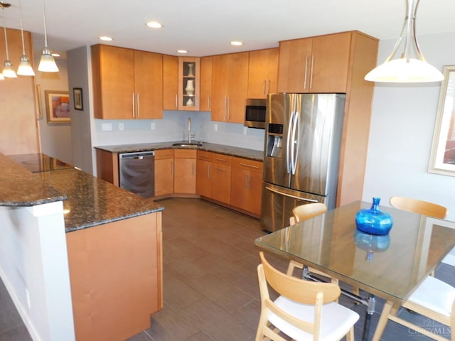 kitchen featuring stainless steel appliances, a sink, dark stone counters, glass insert cabinets, and recessed lighting