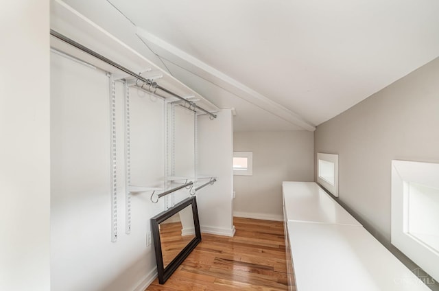 spacious closet featuring light wood finished floors and vaulted ceiling
