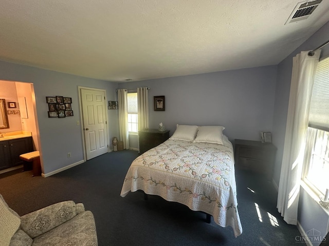 bedroom featuring dark carpet, baseboards, and connected bathroom