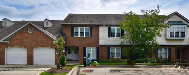 view of property with concrete driveway, a garage, and brick siding