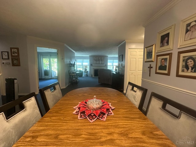 dining area featuring plenty of natural light, crown molding, carpet flooring, and a fireplace