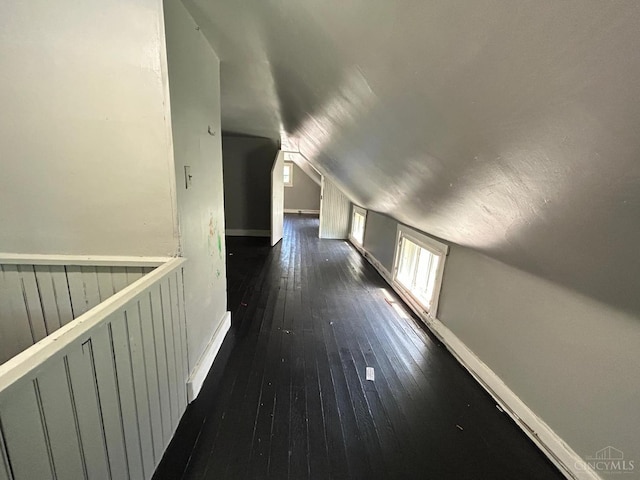 bonus room featuring lofted ceiling, dark wood-type flooring, and baseboards