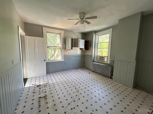 unfurnished room featuring radiator, wainscoting, a ceiling fan, and cooling unit