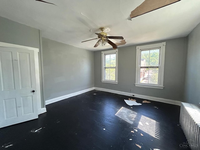 unfurnished room featuring radiator, baseboards, and ceiling fan