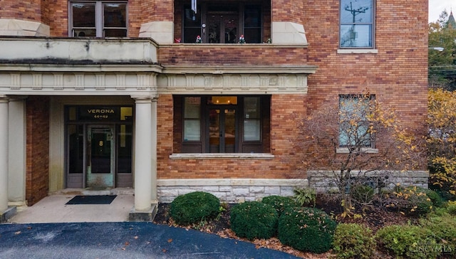 doorway to property featuring brick siding and a balcony