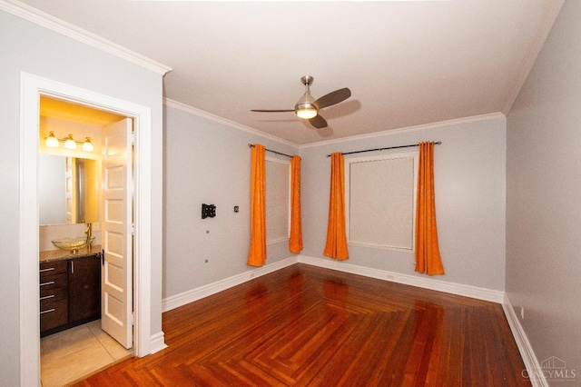 unfurnished bedroom featuring baseboards, ornamental molding, ensuite bath, a ceiling fan, and a sink