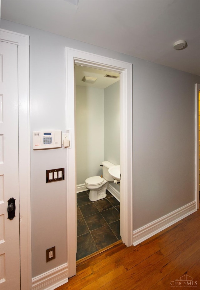 bathroom with toilet, baseboards, and wood finished floors