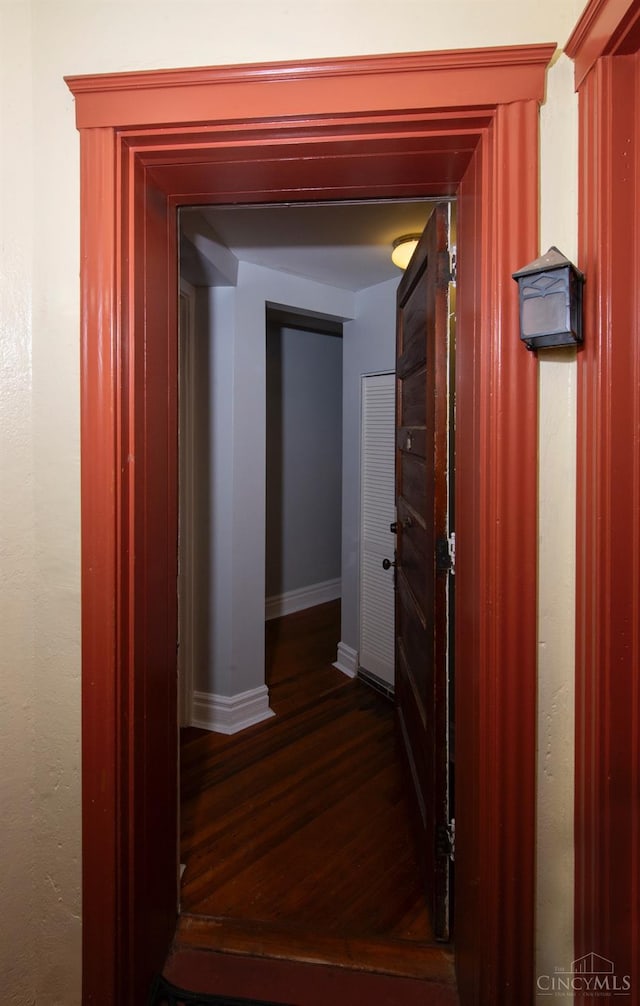 corridor with dark wood-type flooring and baseboards