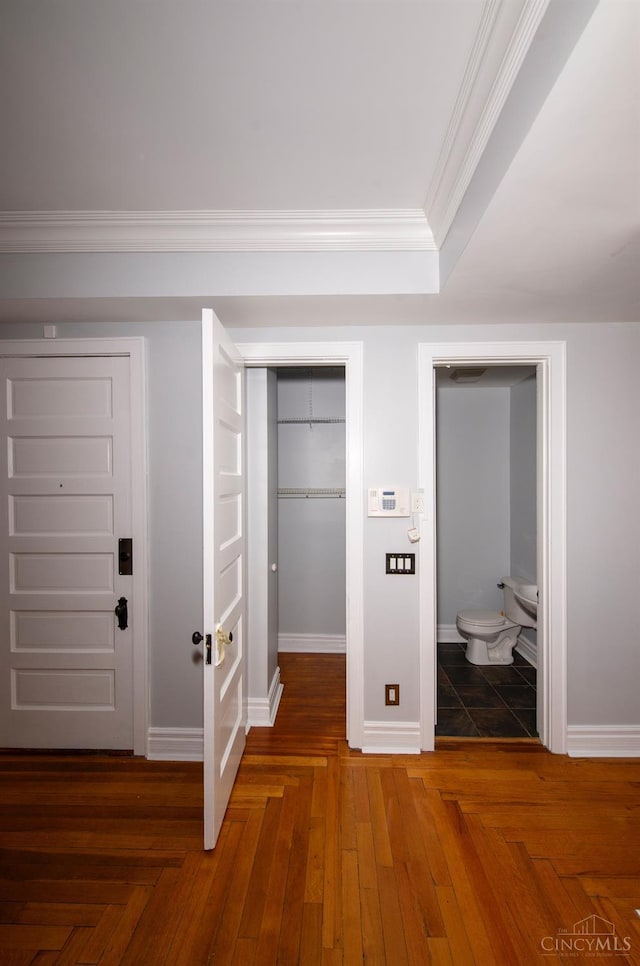unfurnished bedroom with crown molding, baseboards, a closet, ensuite bath, and a spacious closet
