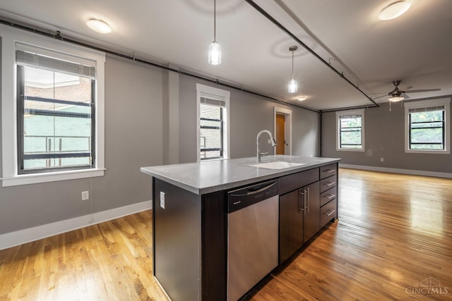 kitchen with a sink, dishwasher, light wood-style floors, open floor plan, and hanging light fixtures