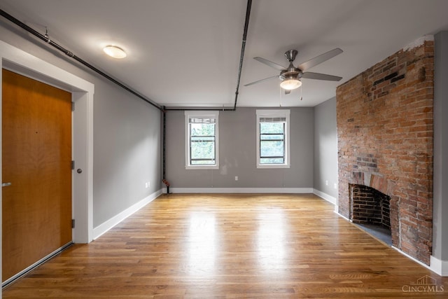 unfurnished living room featuring ceiling fan, wood finished floors, a fireplace, and baseboards