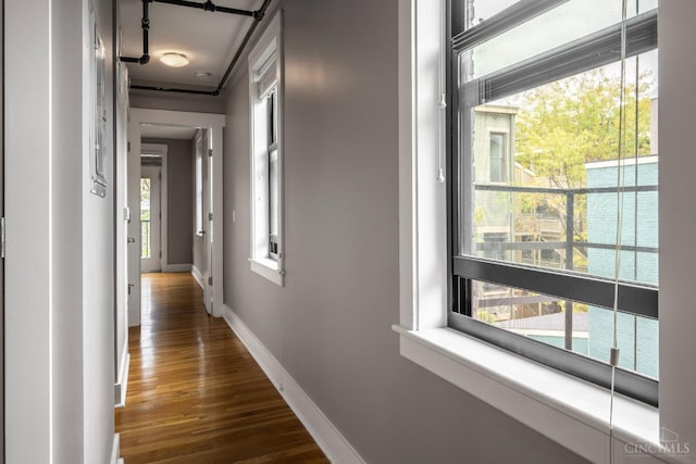 hall featuring dark wood-type flooring and baseboards