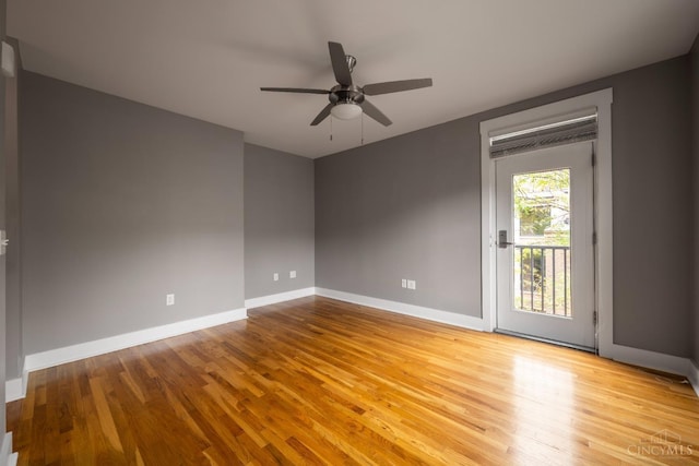 empty room with wood finished floors, a ceiling fan, and baseboards
