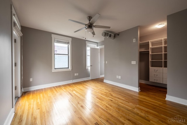 unfurnished bedroom with wood-type flooring, baseboards, and a walk in closet