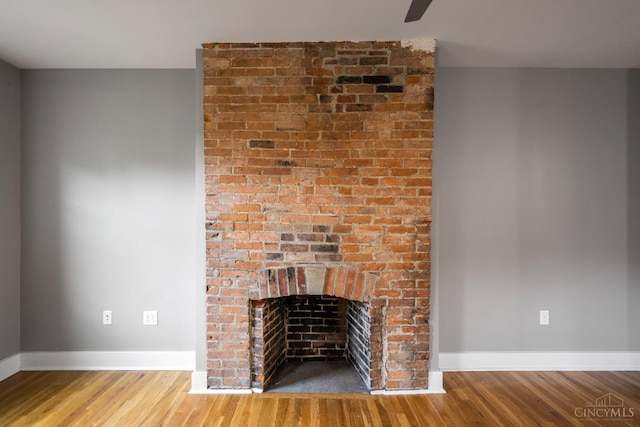 detailed view of wood finished floors, baseboards, and a fireplace