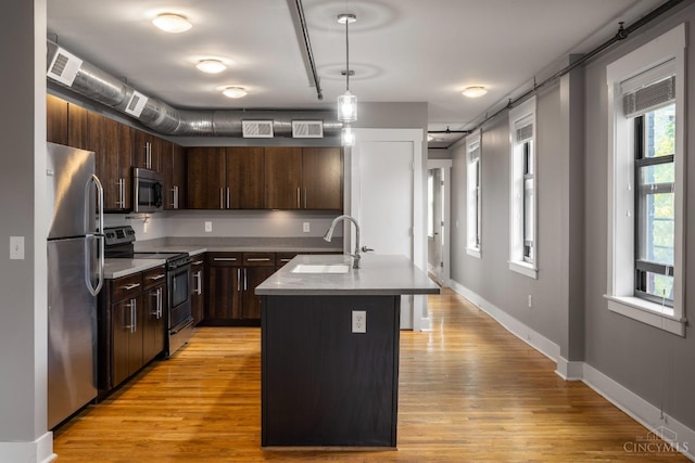 kitchen featuring stainless steel appliances, light wood-style floors, light countertops, and dark brown cabinets