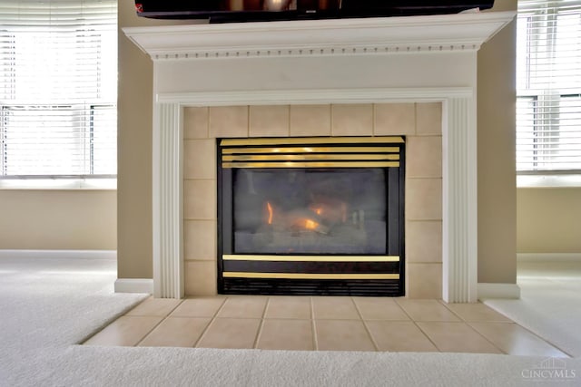 detailed view of carpet floors, a tile fireplace, and baseboards