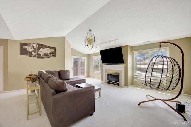 living area with carpet flooring, vaulted ceiling, baseboards, track lighting, and a tiled fireplace