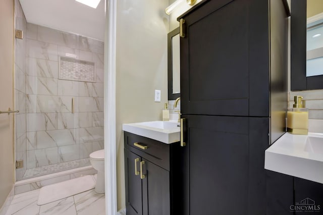 bathroom featuring marble finish flooring, toilet, a stall shower, and vanity